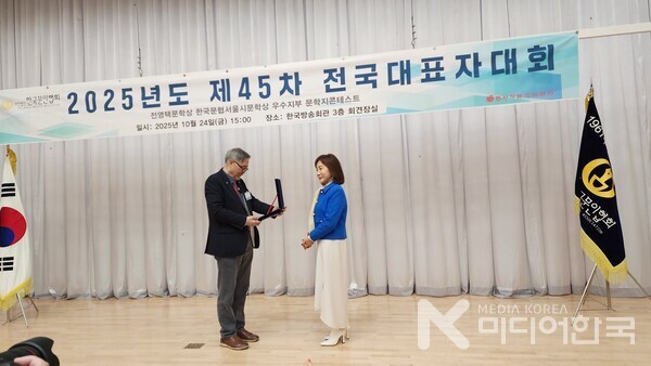 한국문인협회 김호운 이사장이 김선영 시인에게 수상패를 수여하고 있다